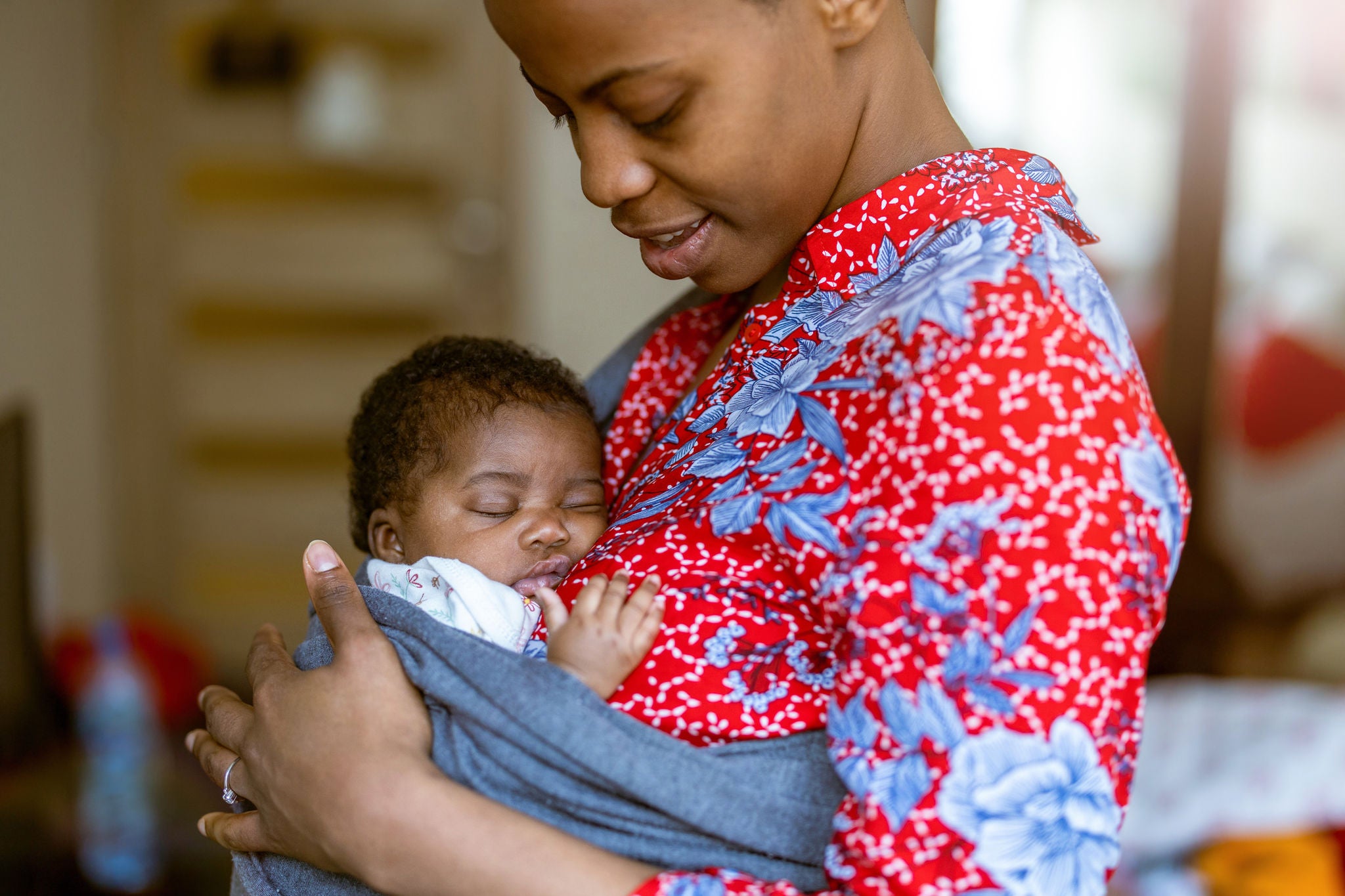 Woman looks down at her newborn wrapped in a baby carrier