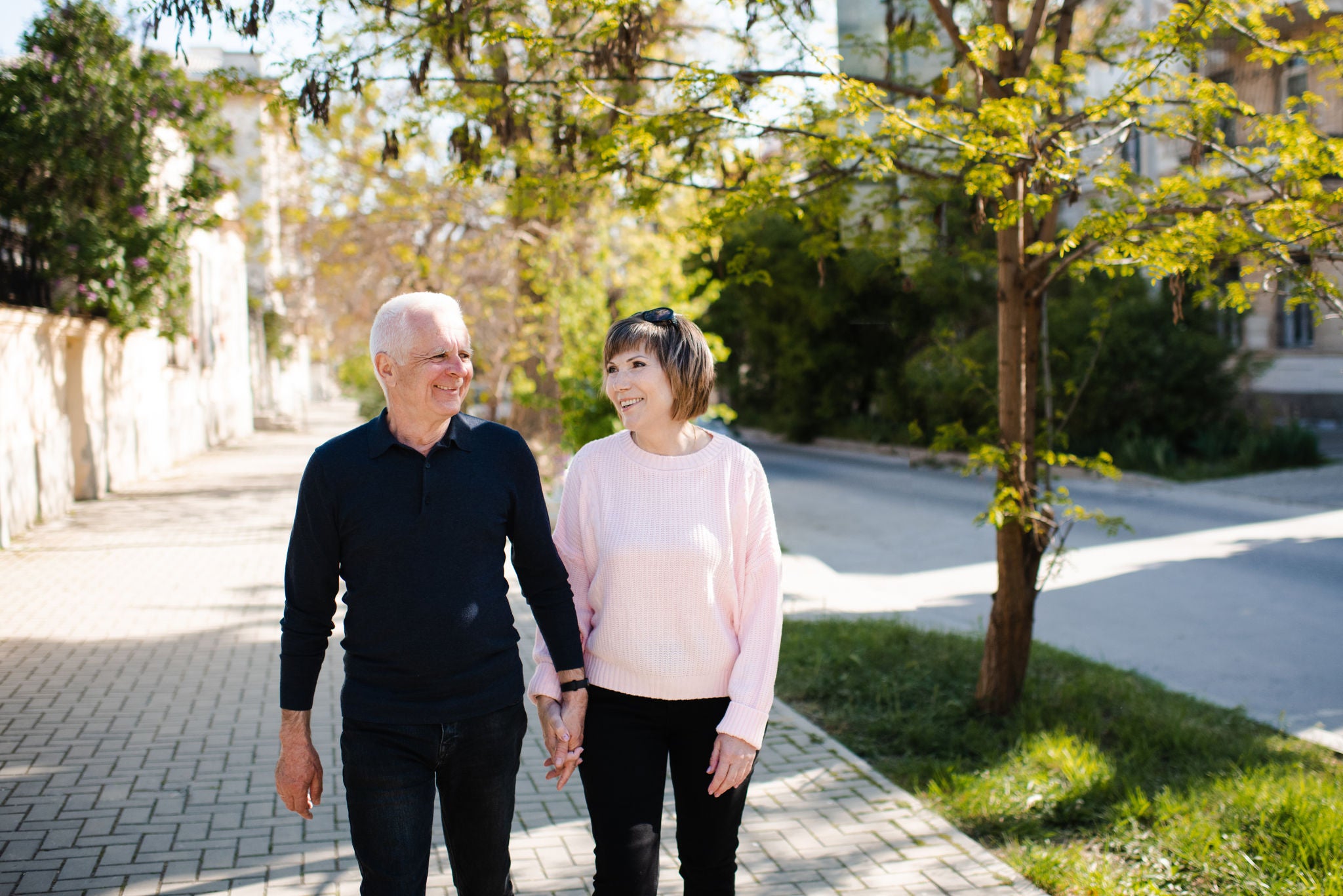 Senior happy couple of stylish man and woman 60-65 year old walking together on streets holding hands at city outdoors. Wellness lifestyle. Happiness.