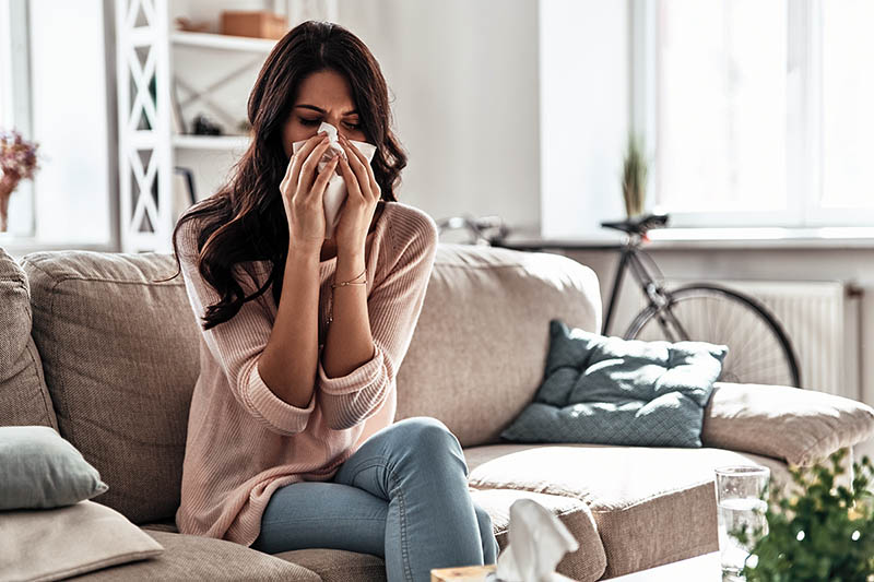 Woman blowing nose from indoor allergens.