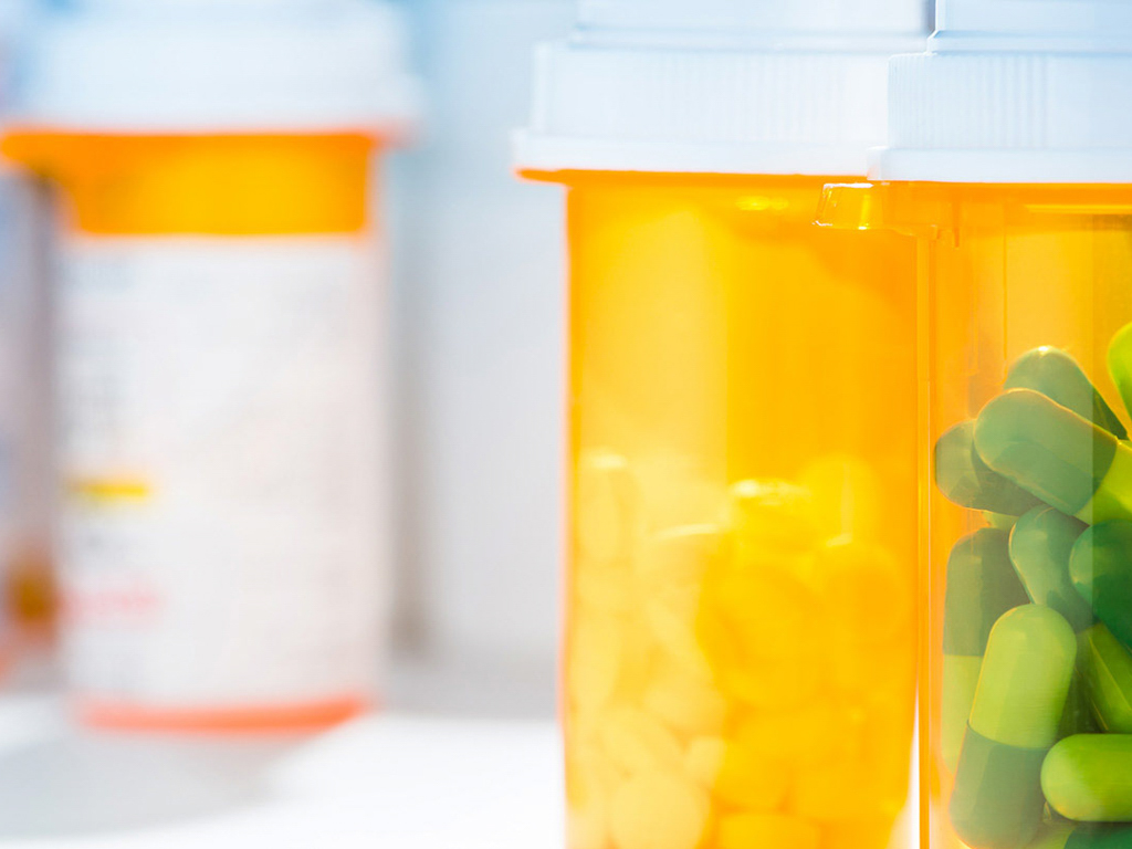 Close up image of a shelf of prescription pill bottles.