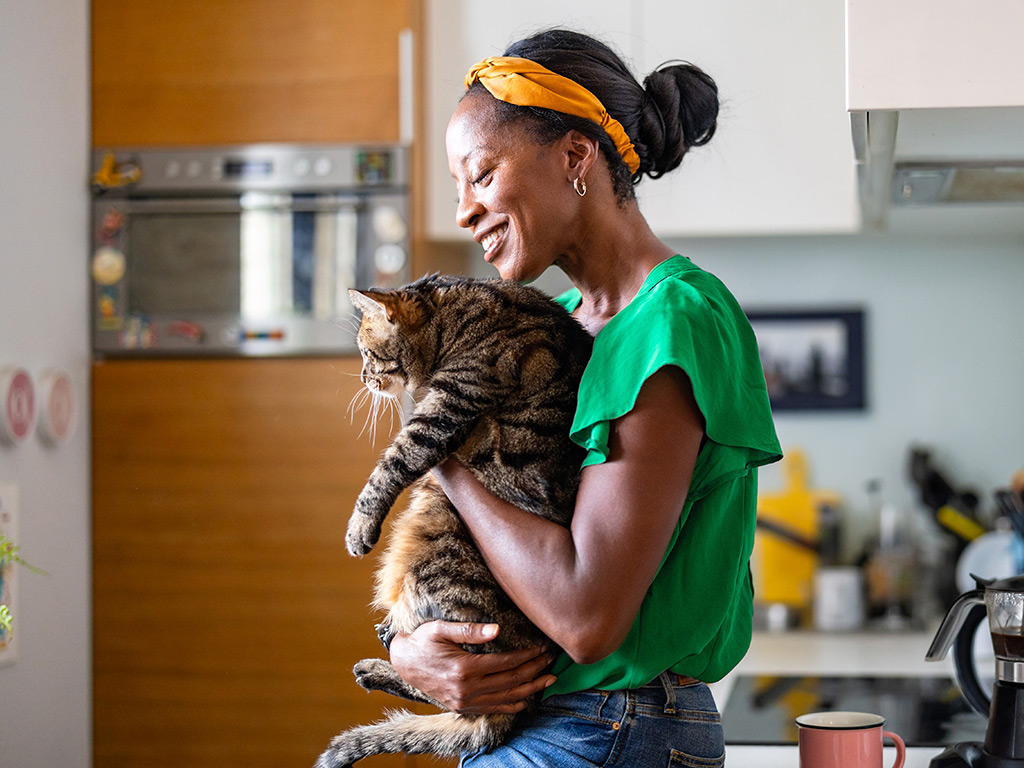 Woman holds a cat in her kitchen