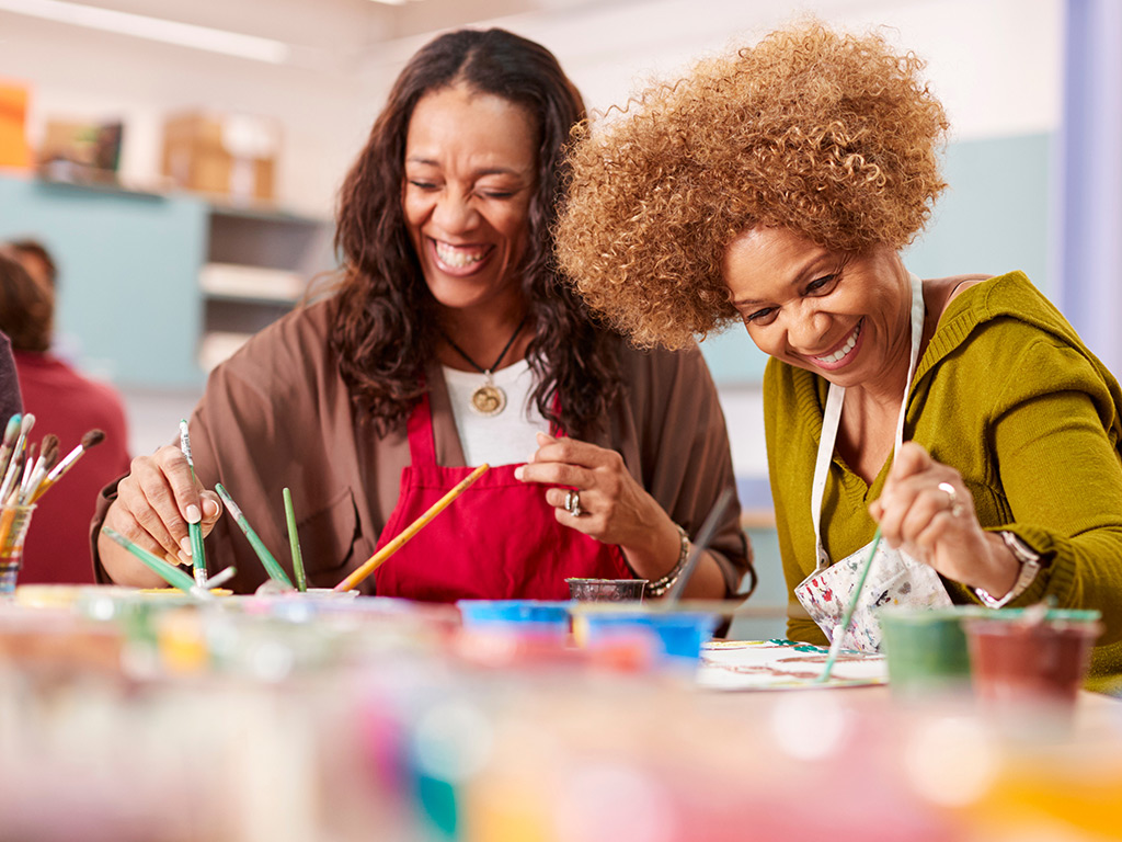 Two women paint in a class.