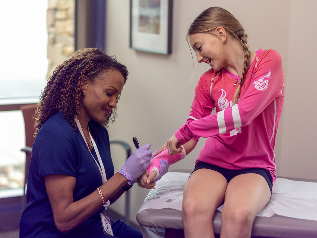 Nurse signing a girl's arm cast at the hospital