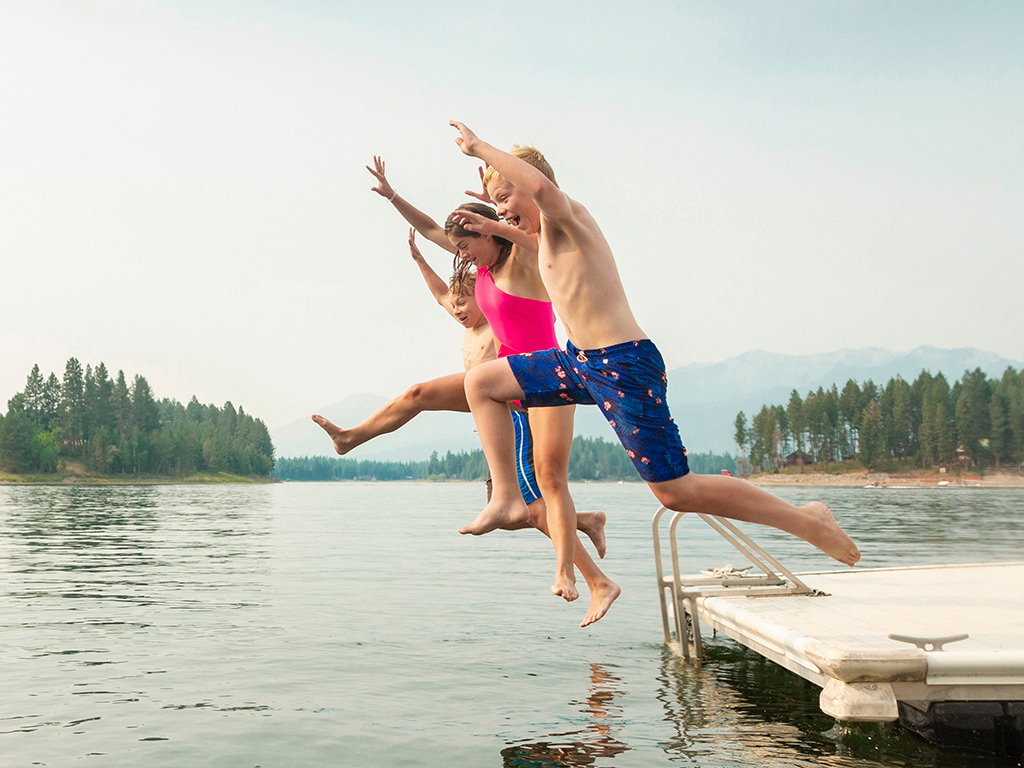 Kids jumping off a dock into a lake