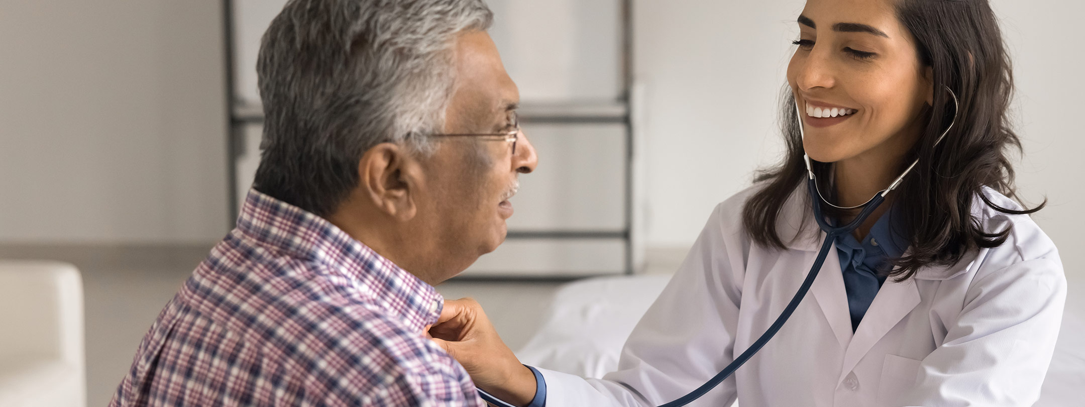 A female doctor listens to her male patient's heart with a stethoscope