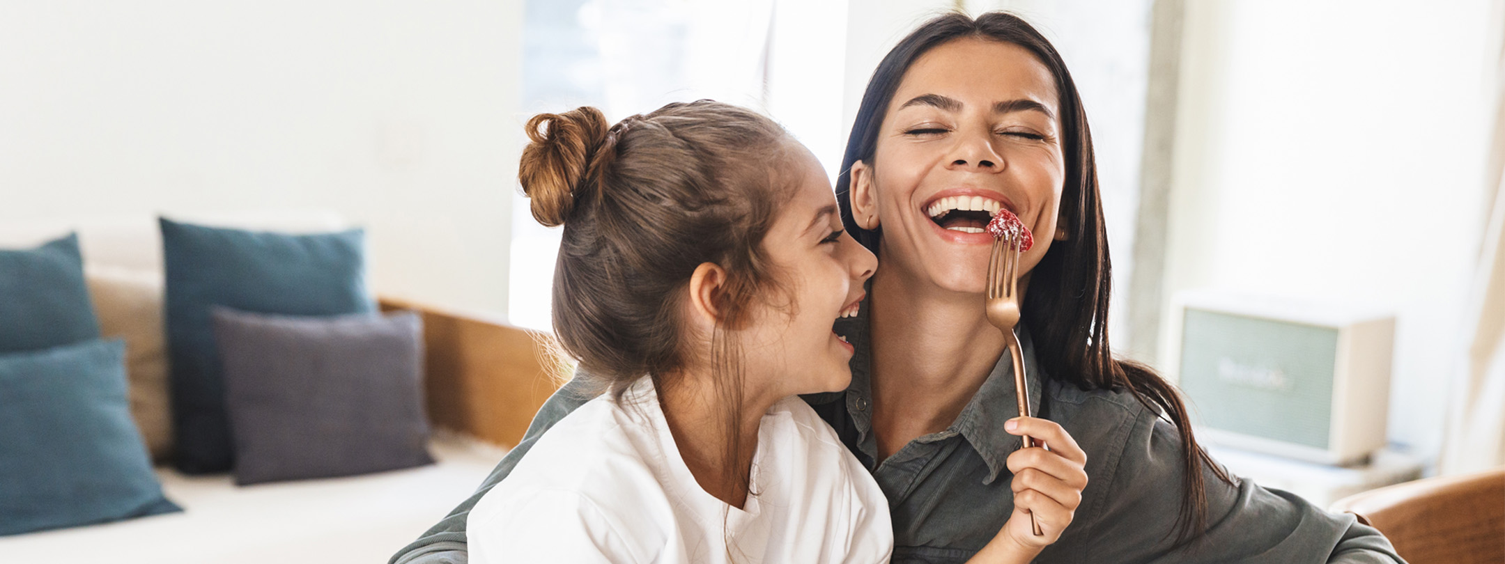 A mother and child are eating a berry and laughing