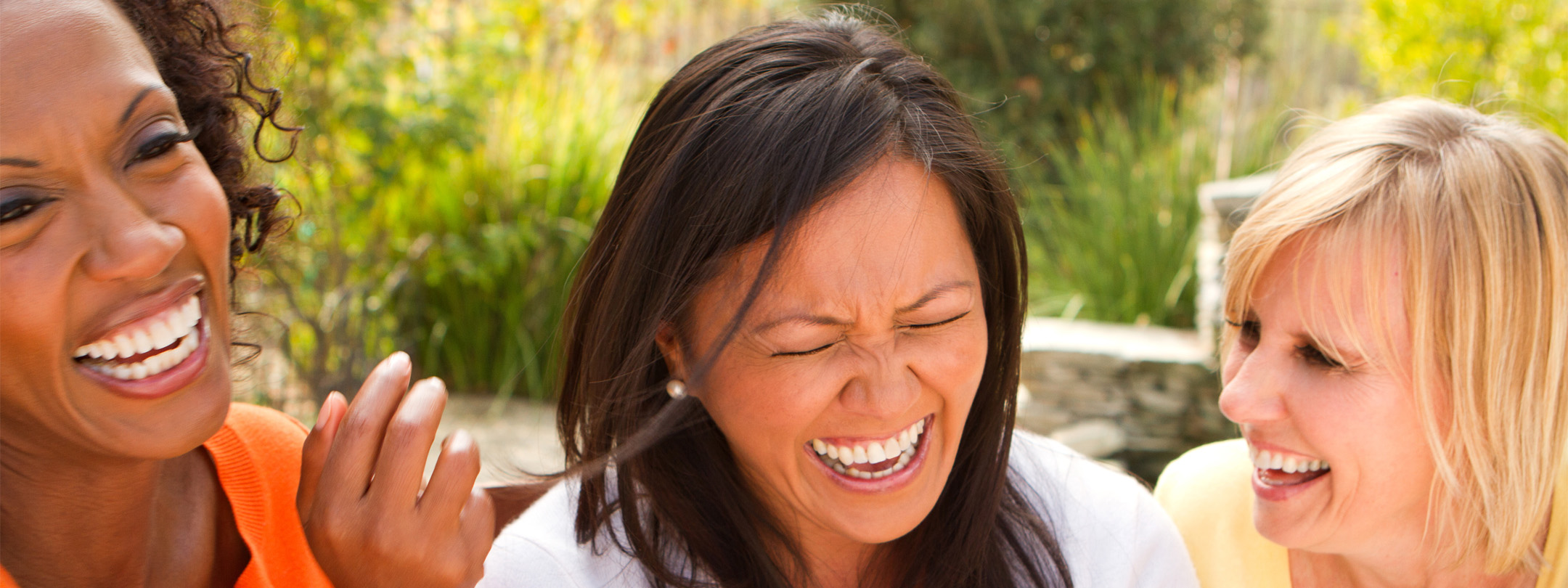 Three women laughing together outside