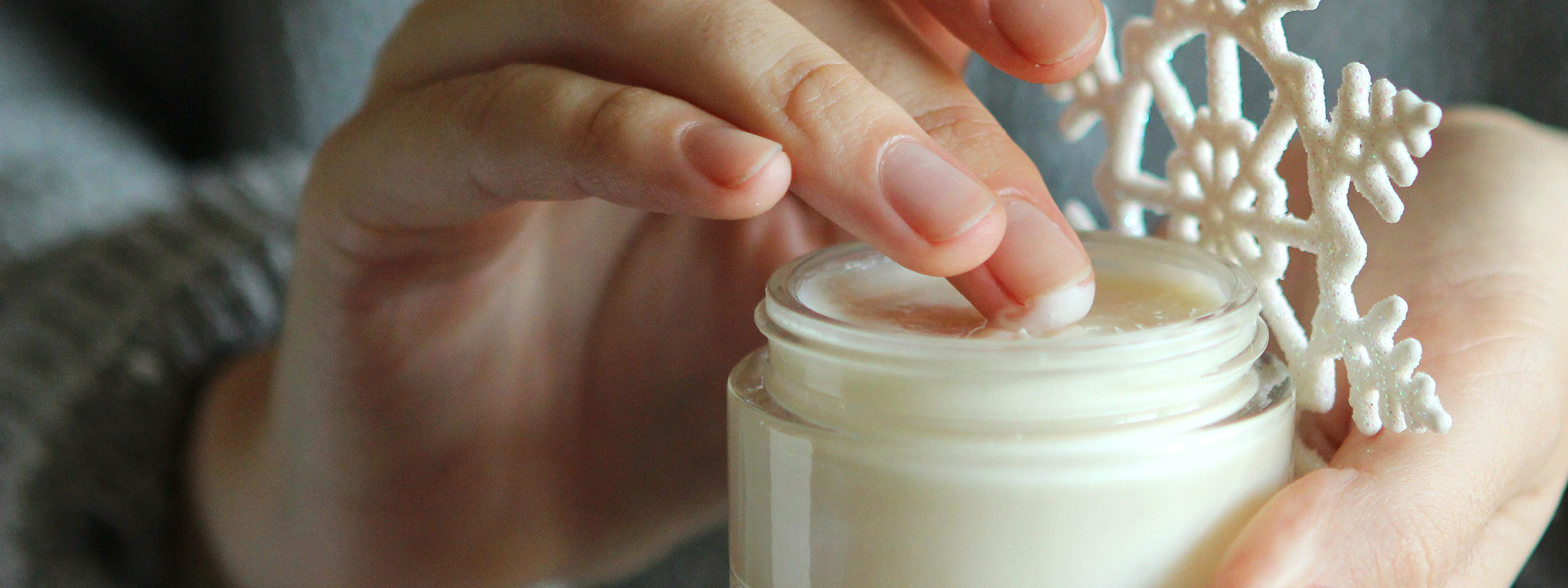 A woman's fingers scoop out cream from a jar in the winter