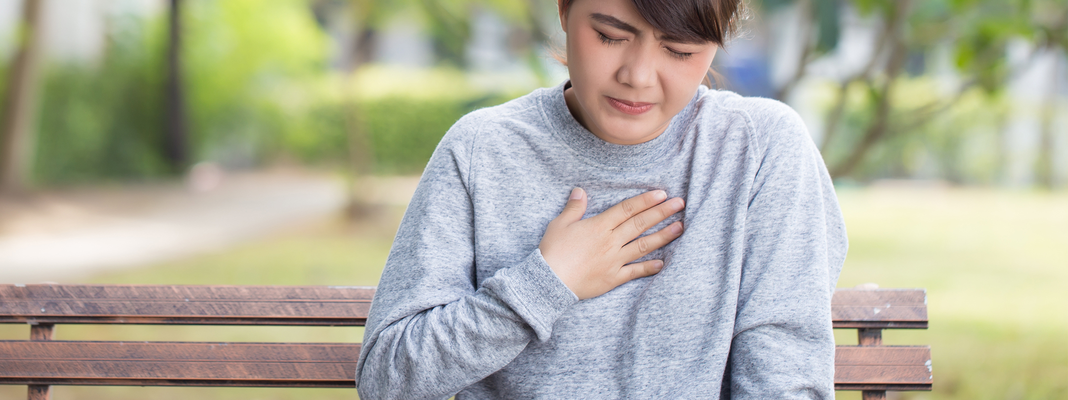 An uncomfortable young woman has hand over her chest in pain