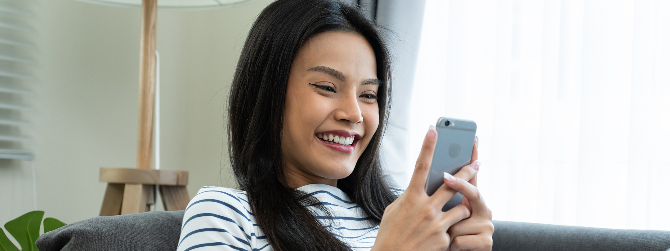 A young woman smiles while looking at her phone at home