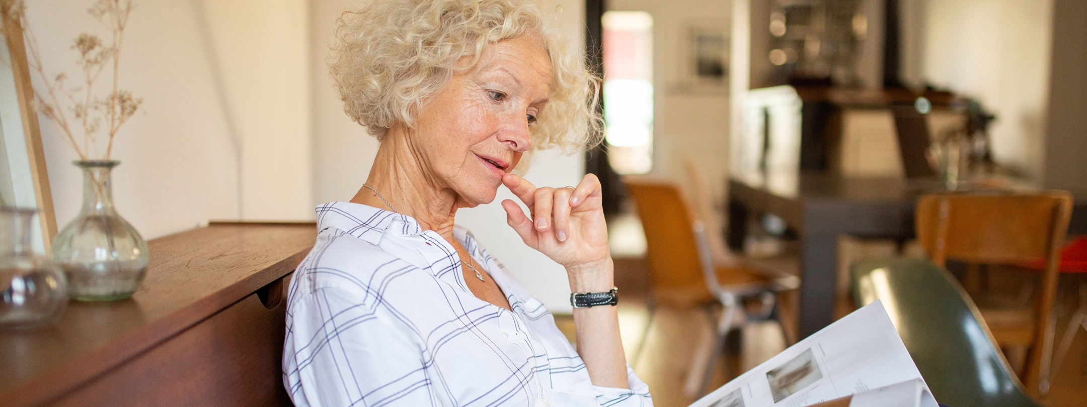 older woman sitting in her home reading a book