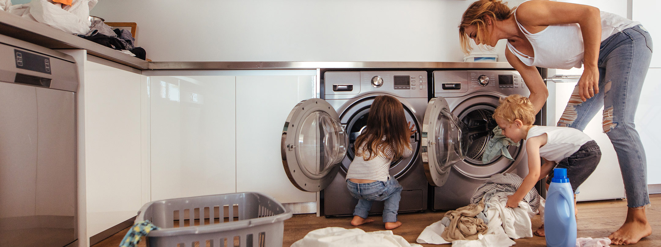 Mother and her two young children doing laundry.