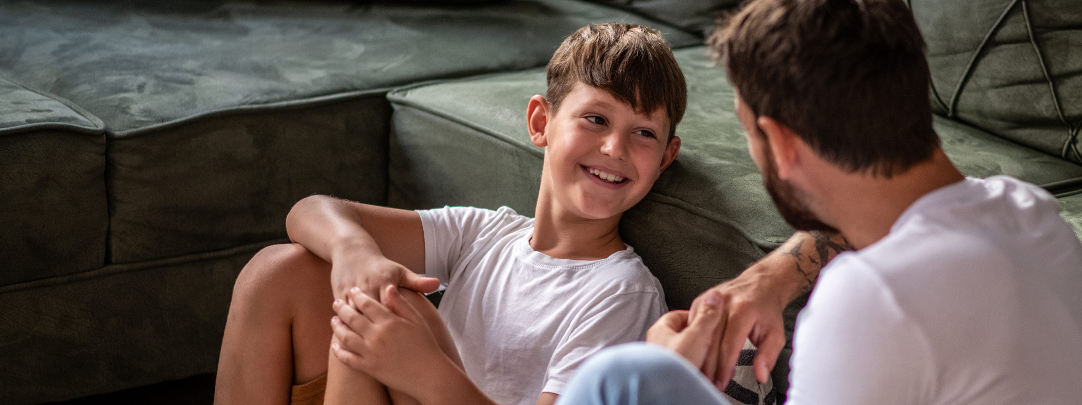 a preteen boy smiles at father near sofa