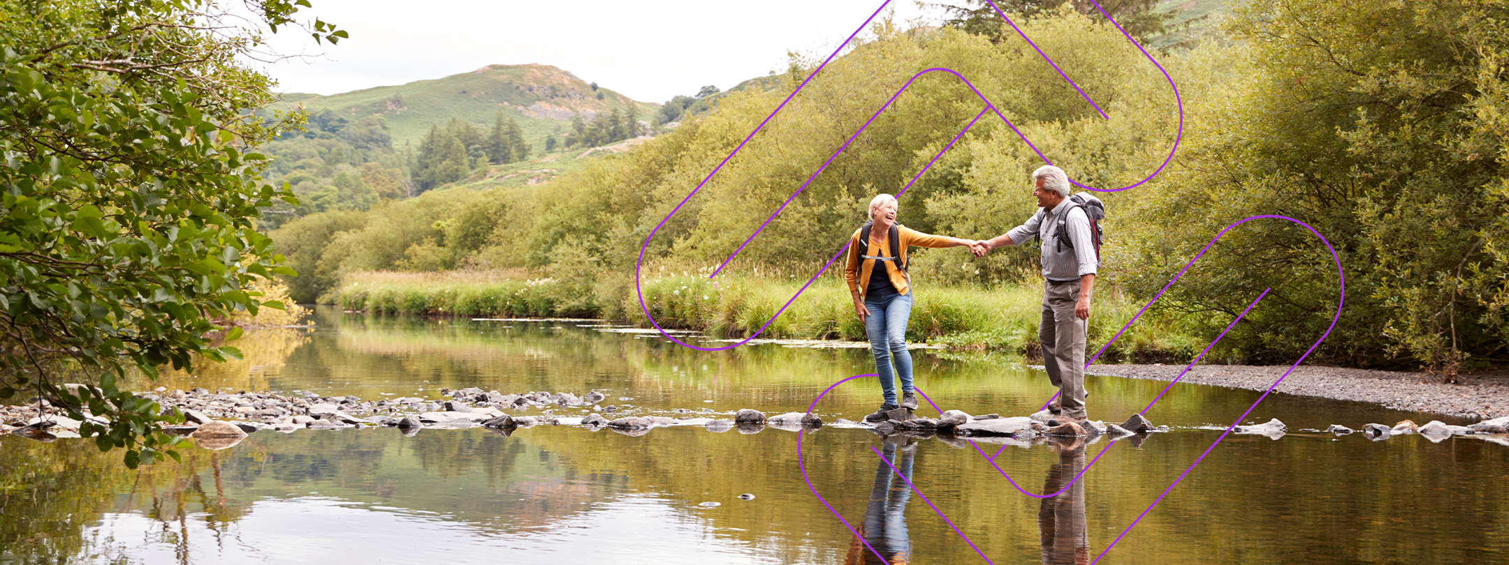 Couple backpacking balancing on stones in the river.