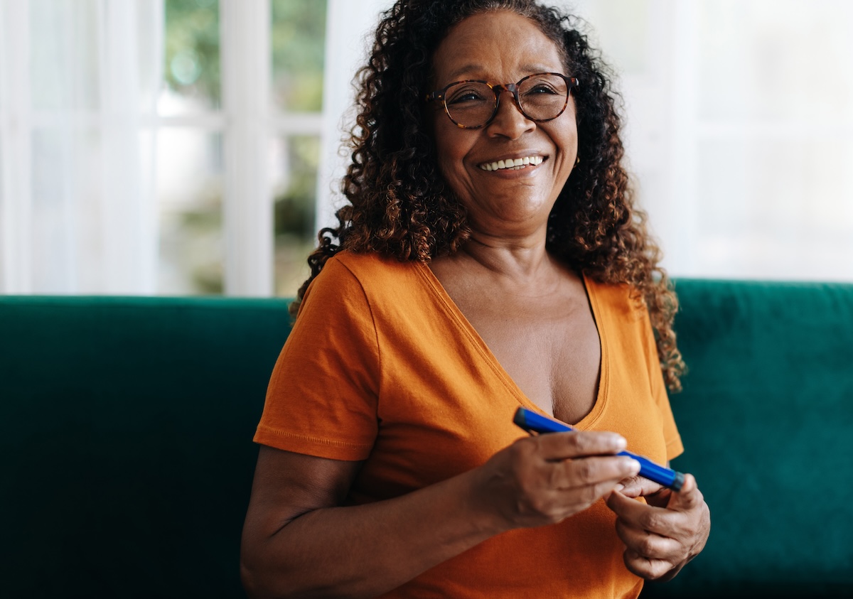 Senior woman with diabetes takes control of her condition by administering insulin to herself. Happy woman using a smart medical device to manage her blood sugar levels and maintain her health at home.