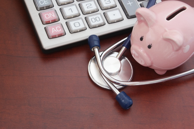piggy bank sitting on a table with a stethoscope and a calculator