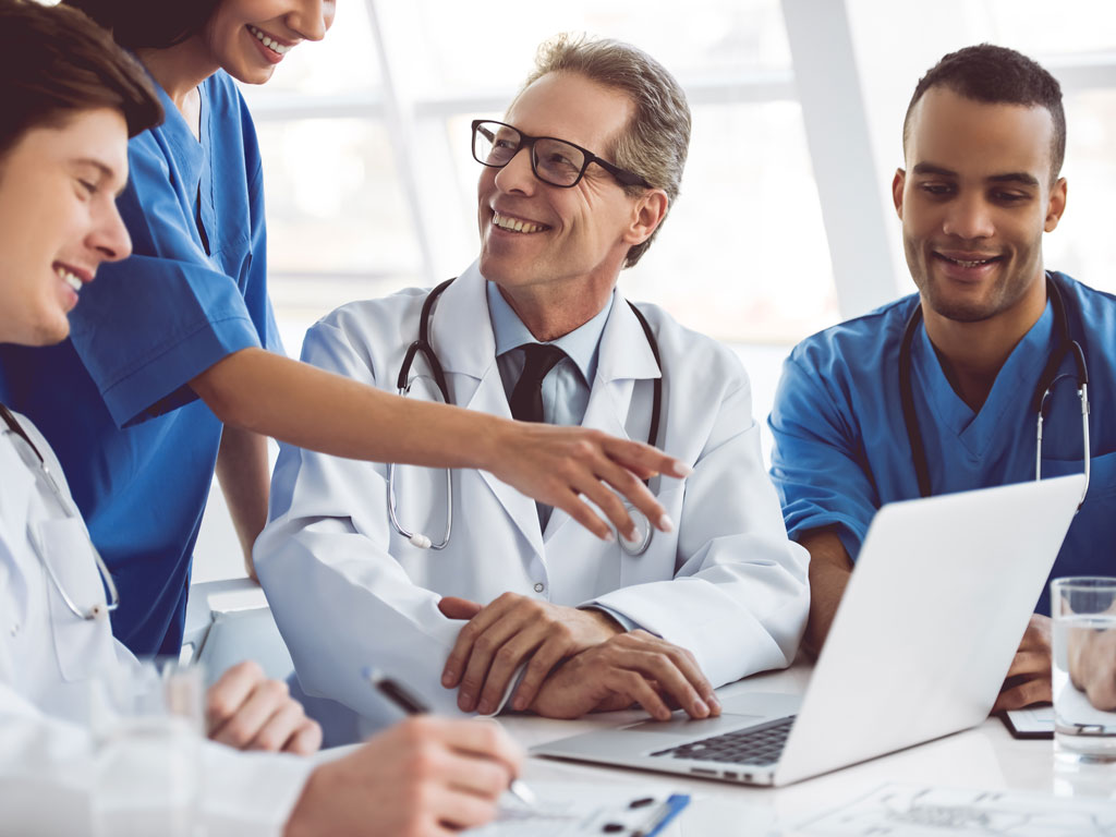 Group of medical providers looking at a laptop computer