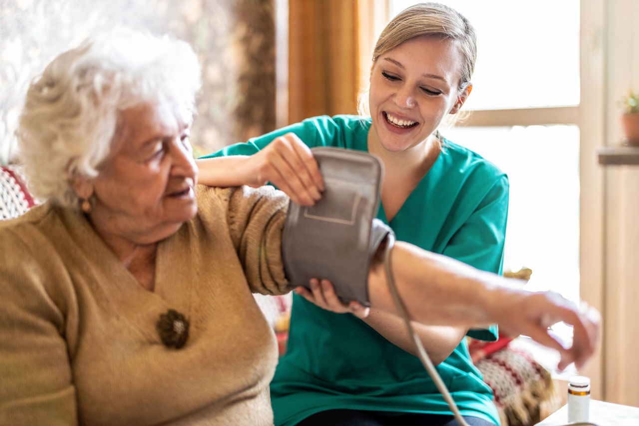 Nurse putting blood pressure cuff on elderly woman's arm